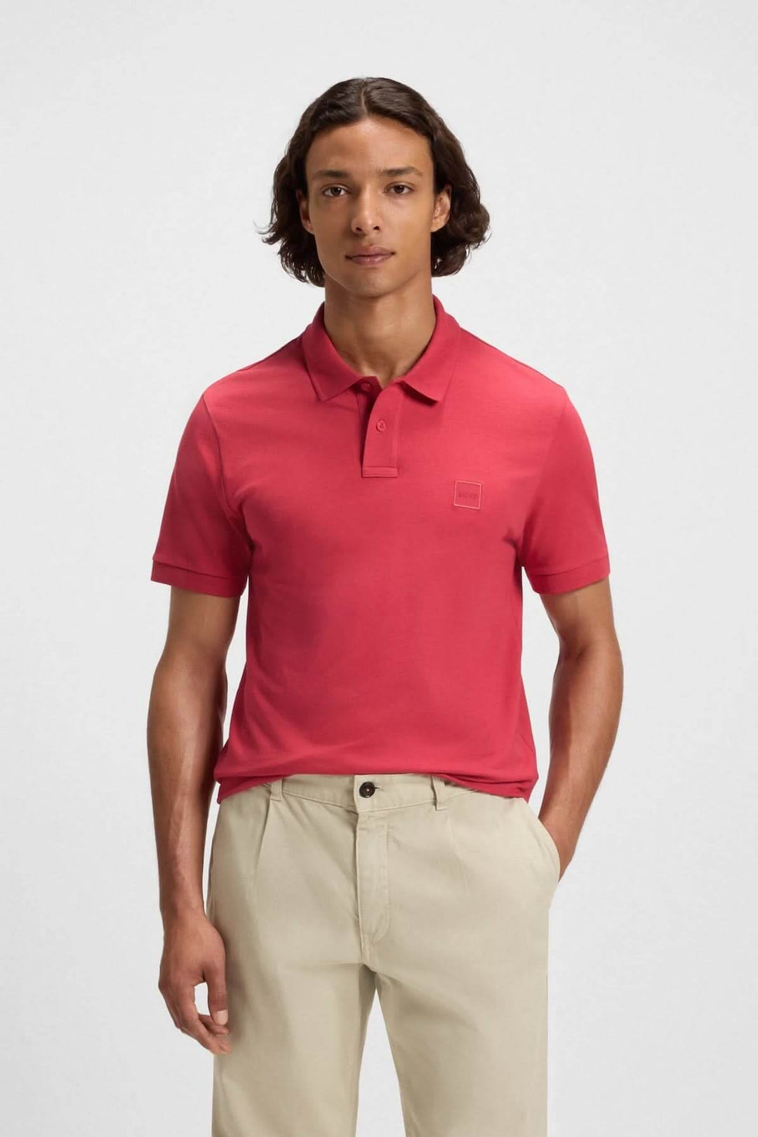 Homme portant un polo rouge à logo Boss, col polo et manches courtes, style casual-chic.
