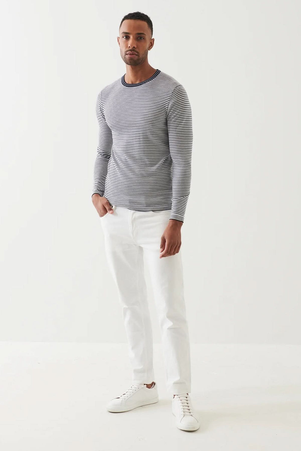 Chandail à rayures intemporel en coupe ajustée, porté avec un pantalon blanc et des baskets blanches.