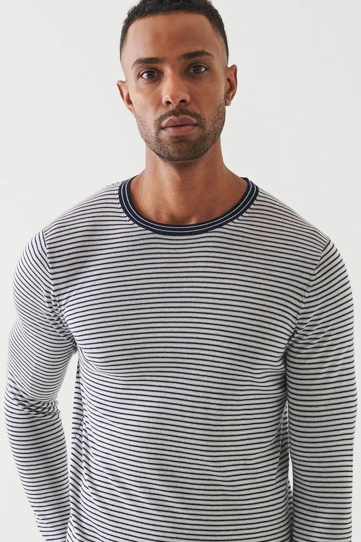 Homme portant un chandail à rayures horizontales, encolure ronde, coupe ajustée et tricot souple.