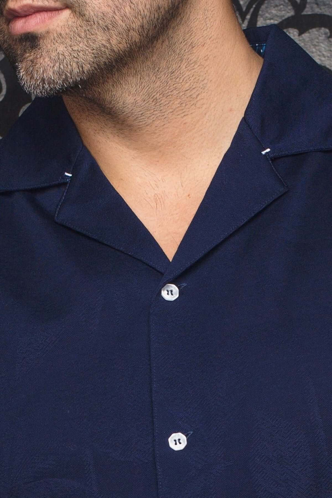 Chemise Brahea à col cubain, tissu texturé bleu marine, patte de boutonnage simple, style élégant pour sorties estivales.