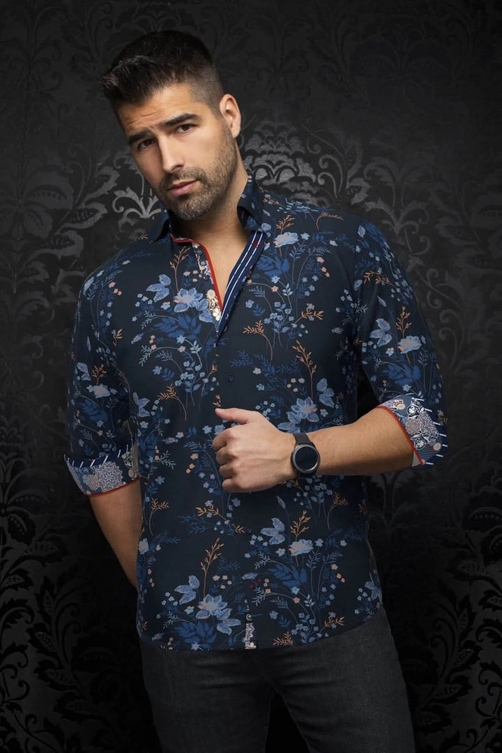 Homme portant une chemise florale élégante avec détails contrastants sur fond sombre.