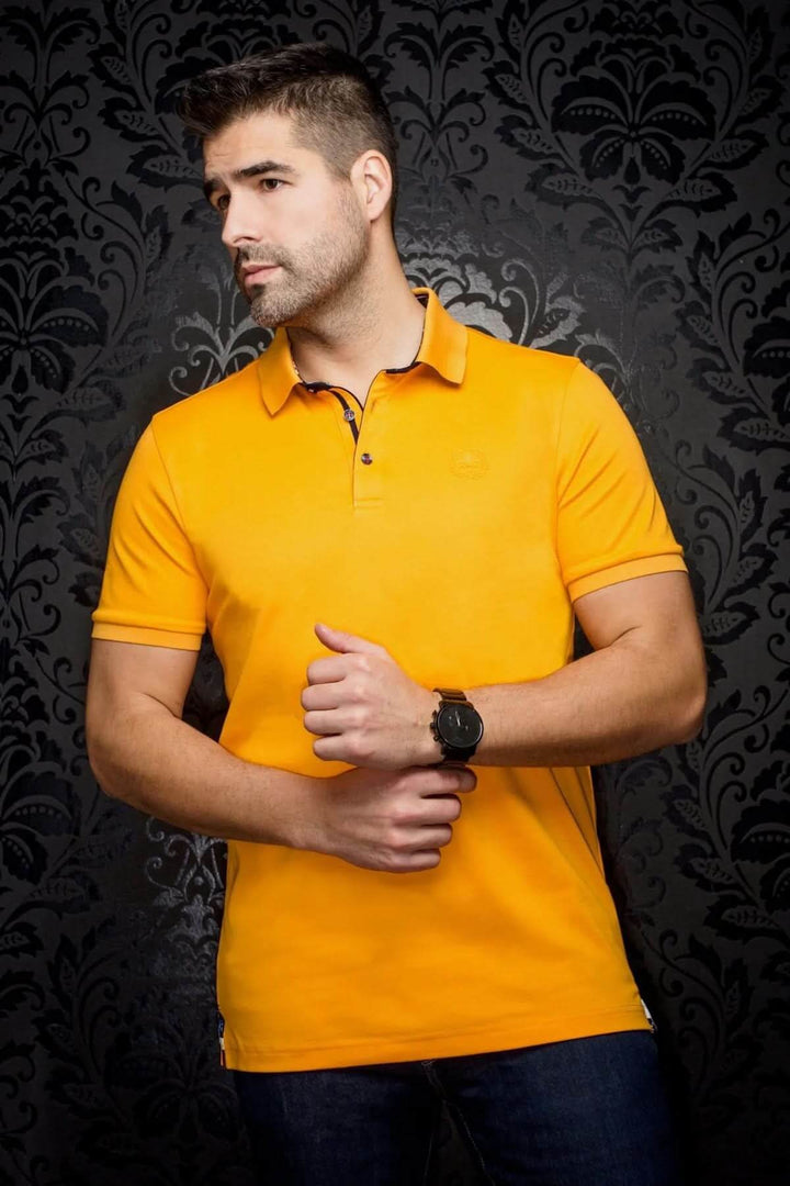 Homme portant un polo uni orange, style épuré avec col contrastant, sur fond noir décoratif.