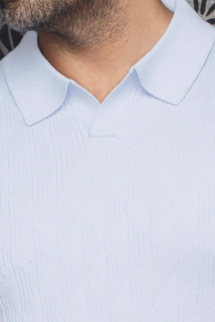 Polo Lowick en maille fine, col ouvert, couleur bleu clair, avec texture discrète et manches courtes.