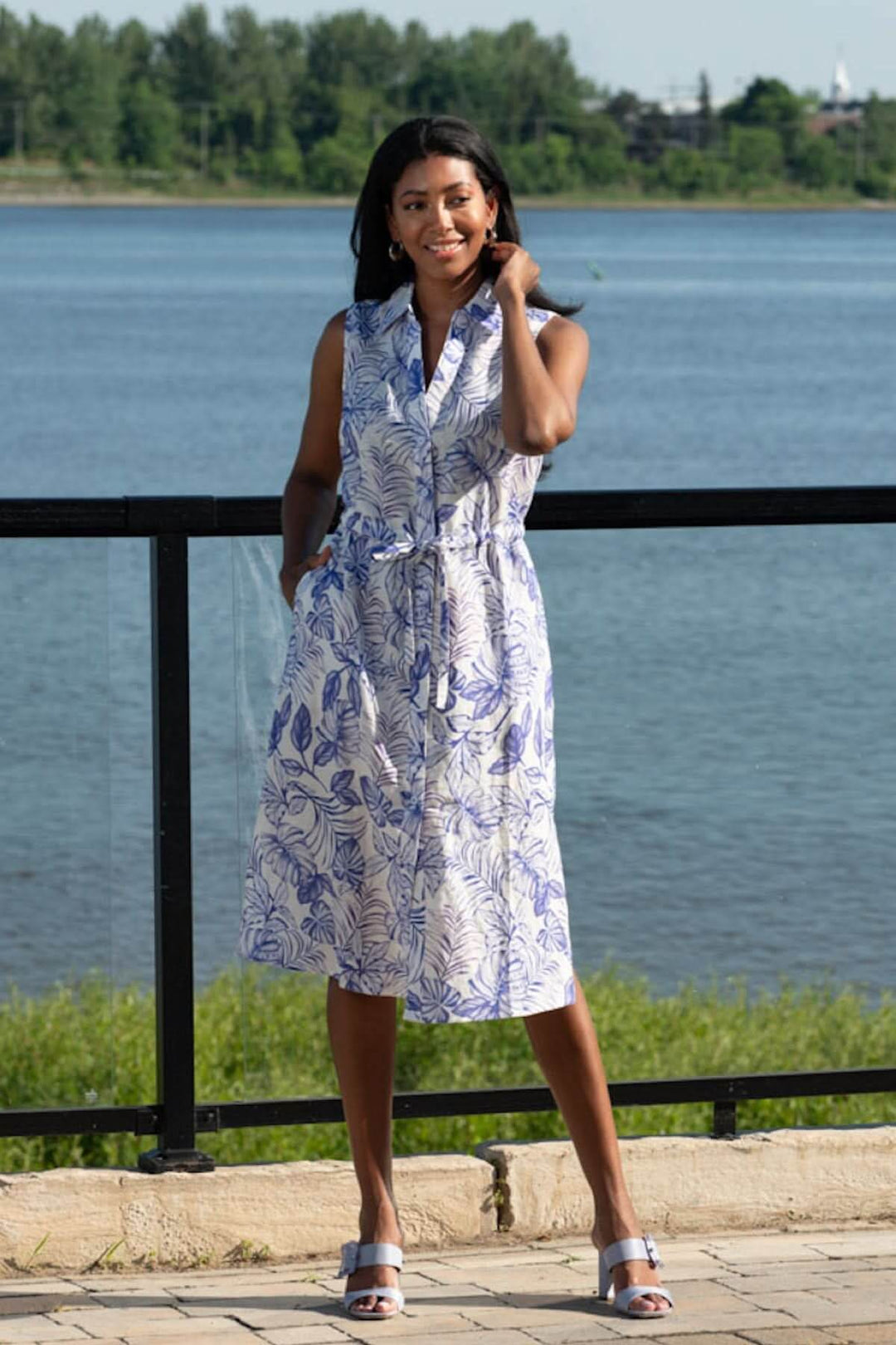 Robe chemise sans manches en imprimé feuillage bleu et blanc, silhouette fluide au bord de l'eau.