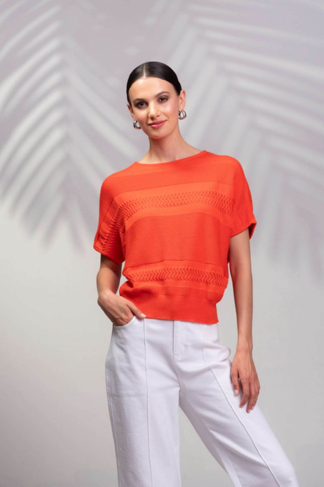 Tricot en coton orange à manches raglan, style décontracté avec détails en point, porté par une femme.