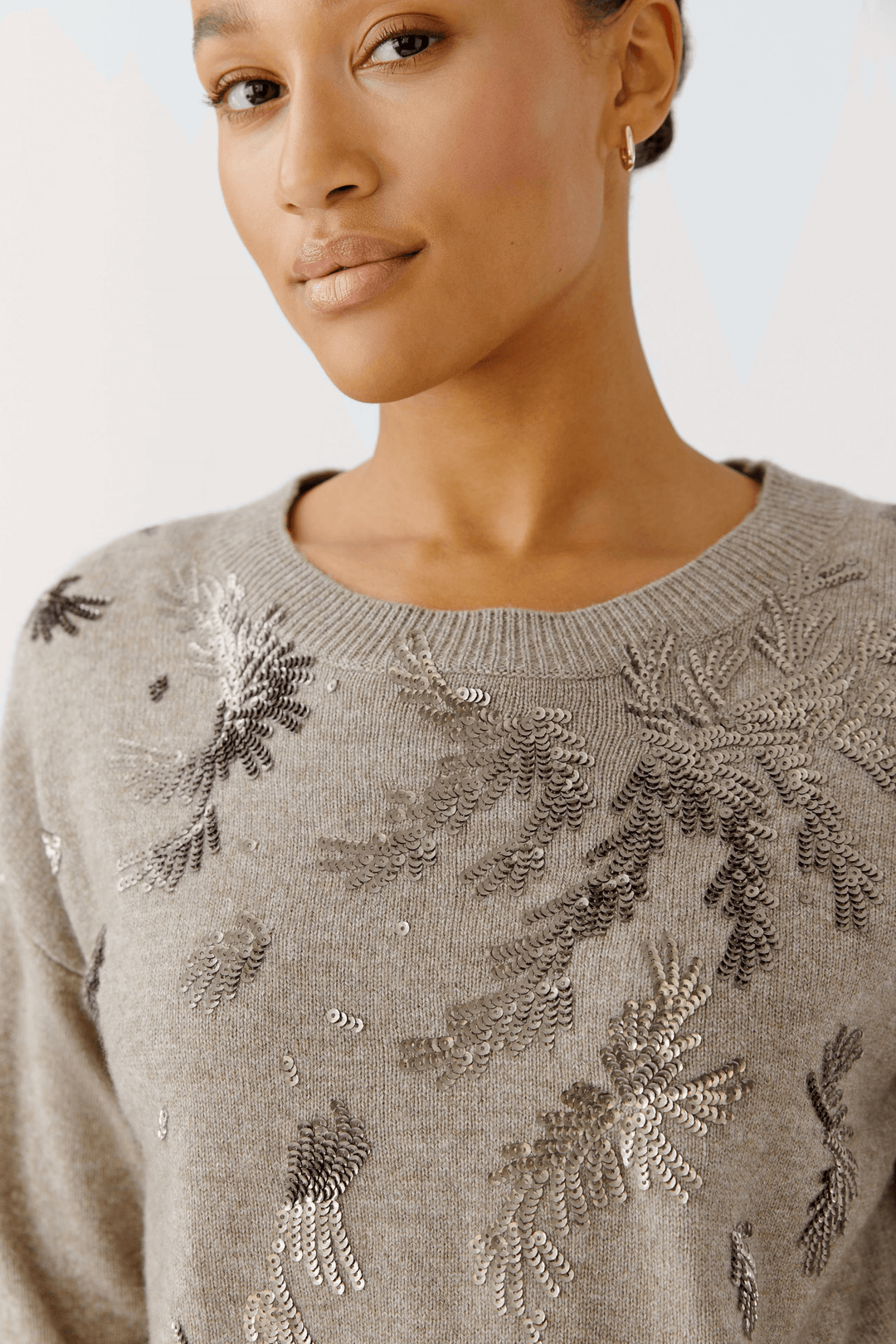 Femme portant un chandail broderies avec motifs scintillants et encolure ronde, coupe droite élégante et confortable.