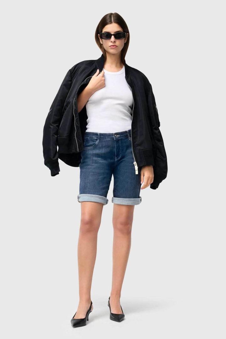 Femme en bermuda denim, débardeur blanc et veste noire, style décontracté chic pour l&