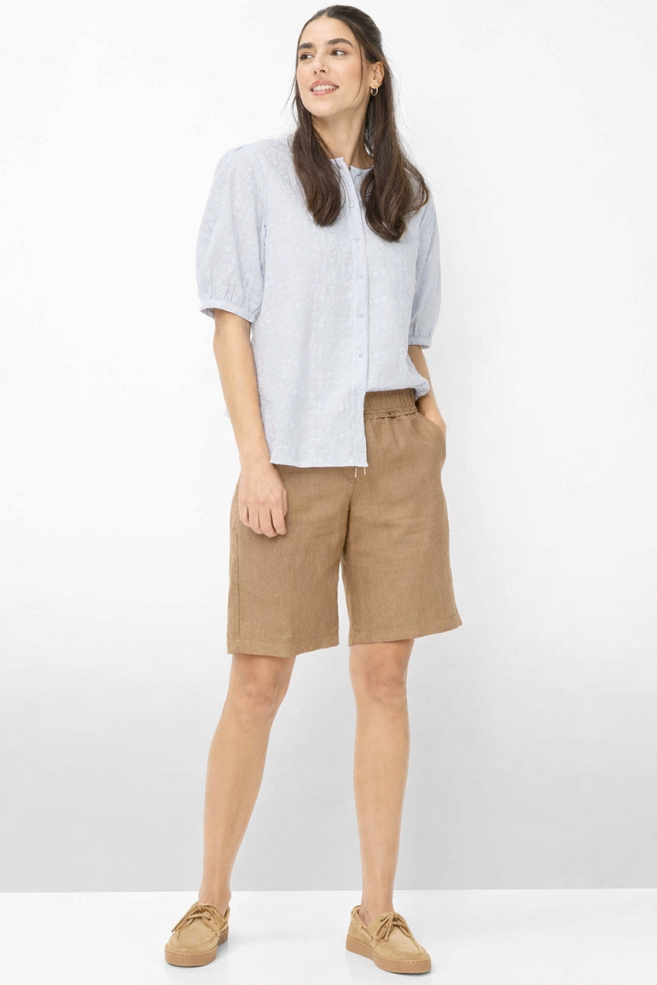Femme portant des Bermudas en lin MEL B avec chemise et sandales, look décontracté sophistiqué.