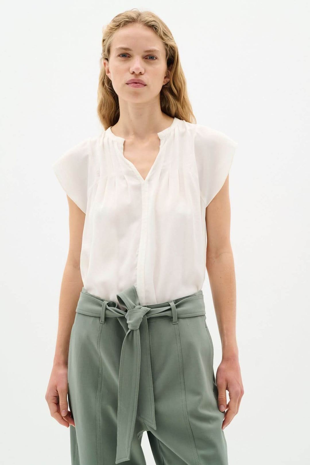 Blouse Cidenza légère et fluide avec encolure plissée et manches volantes, portée avec un pantalon taille haute.