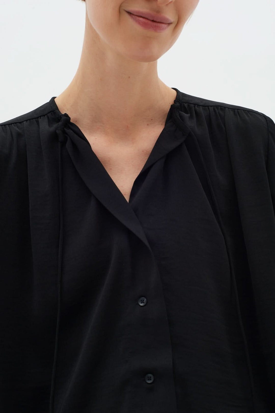 Blouse noire Mato à manches longues et encolure nouée, élégance et sophistication.