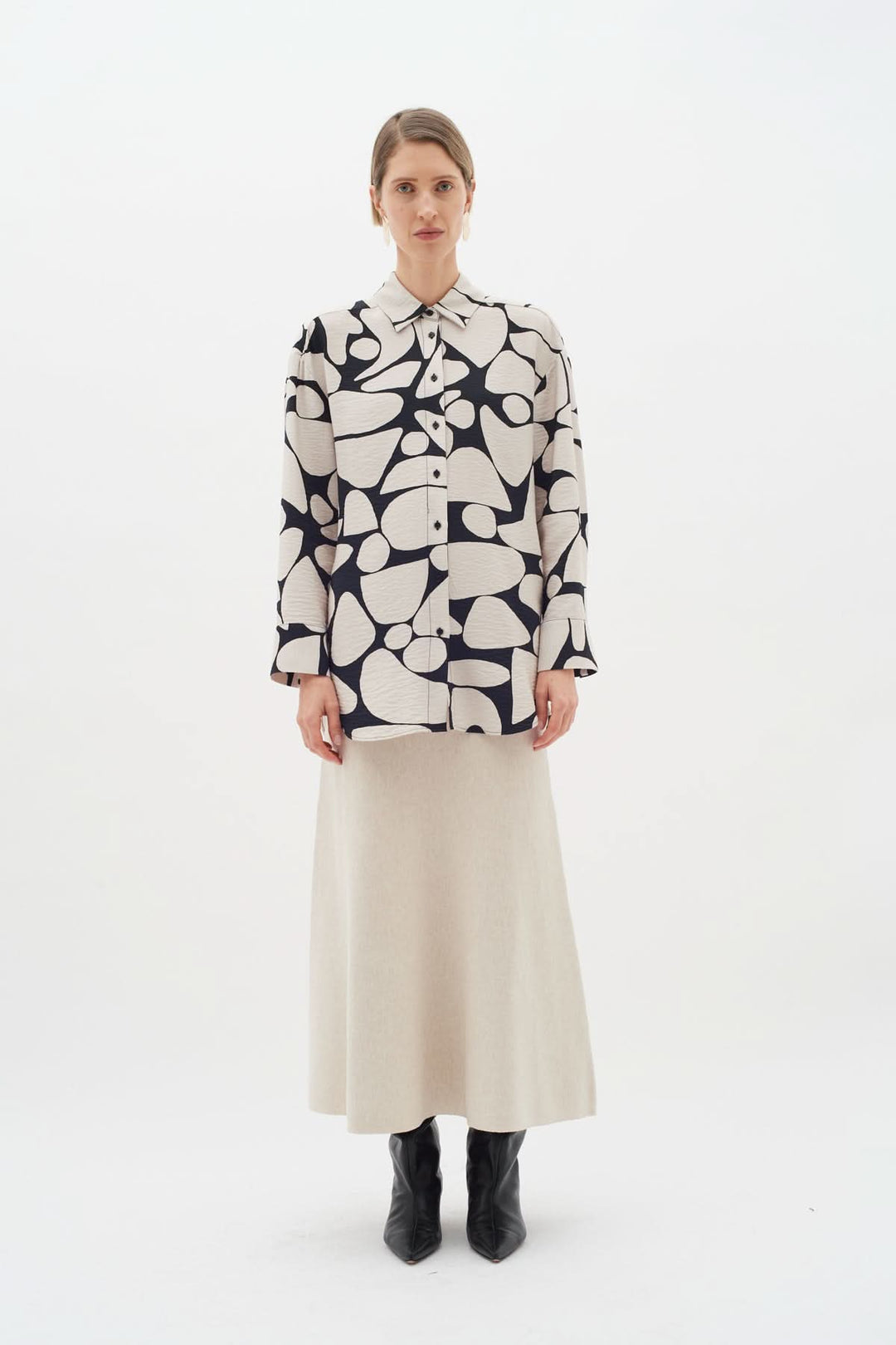 Blouse Metta avec imprimé abstrait, col classique et manches longues, portée par un mannequin avec jupe beige.