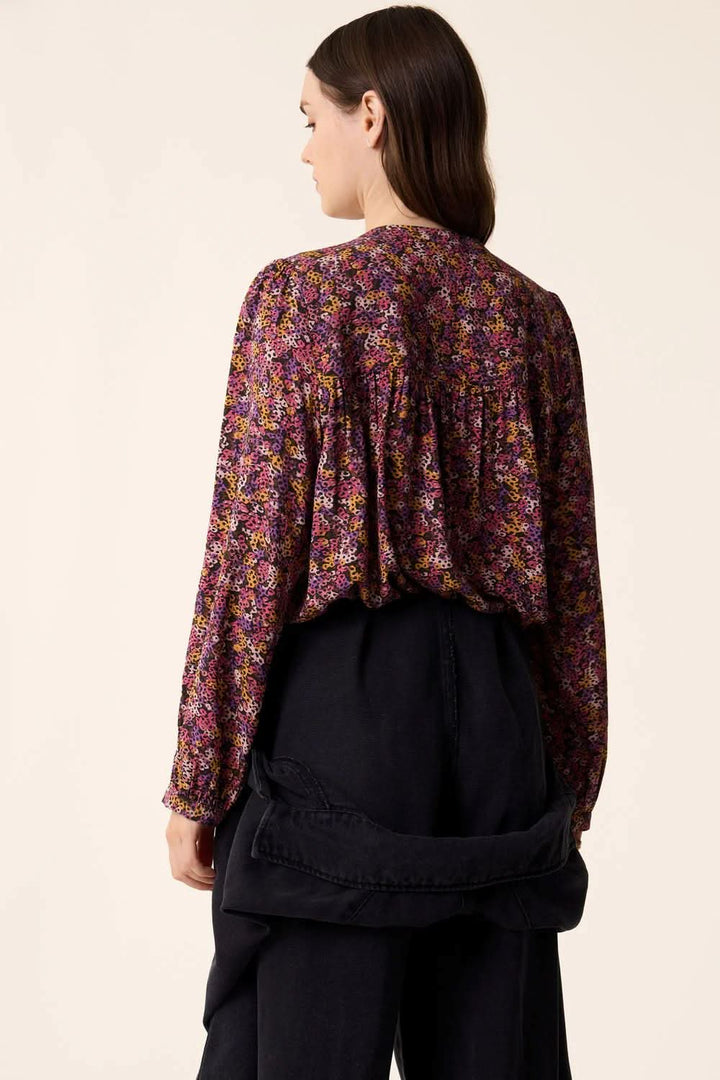 Vue arrière de la blouse Tamtam à manches longues, en motif floral, portée avec un pantalon noir.