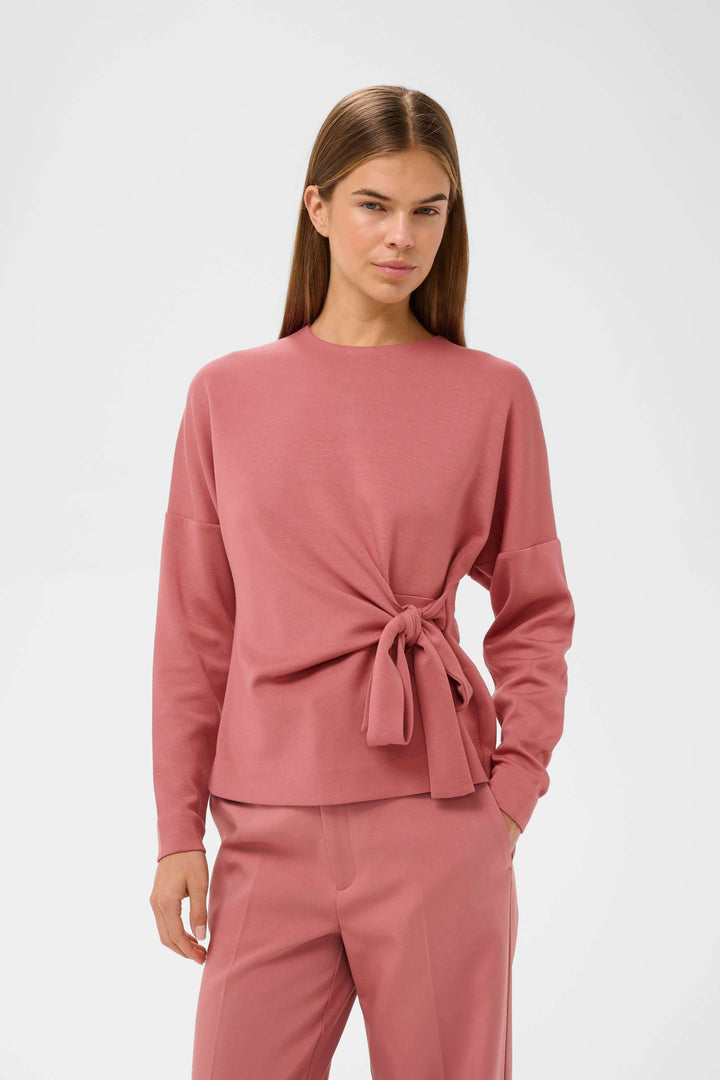 Blouse Tricent en design contemporain avec détail noué, silhouette féminine et élégante, portée par un mannequin.