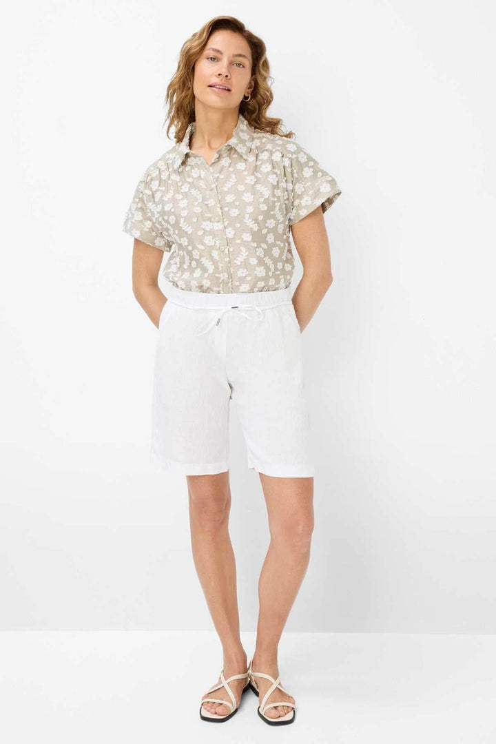 Femme portant une blouse à motifs floraux légers et un short blanc, parfait pour l'été.