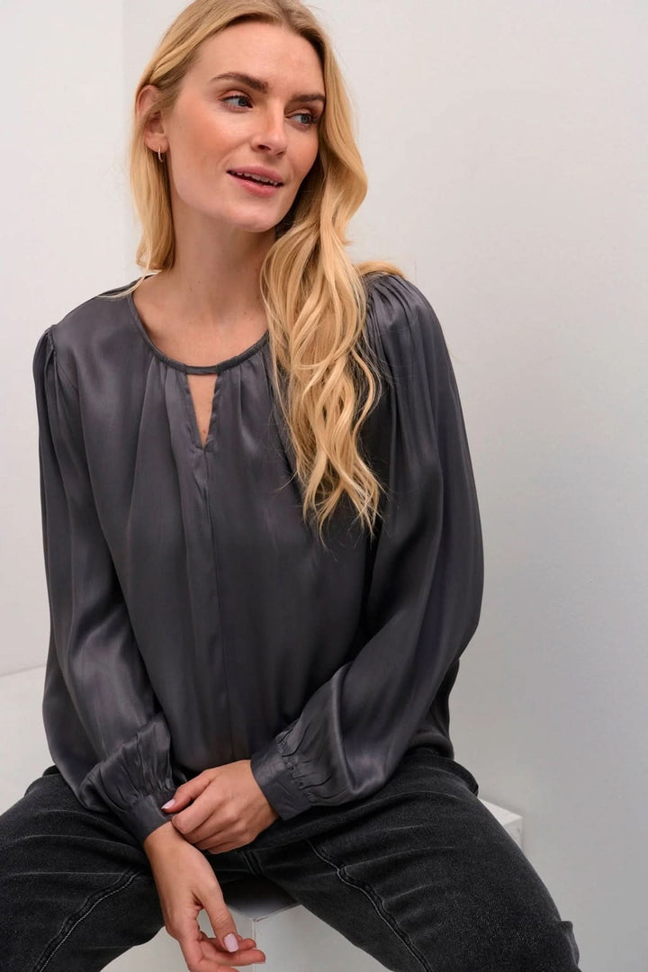 Blouse Viria grise à manches longues avec col en goutte d'eau, élégante et sophistiquée, portée par une femme.
