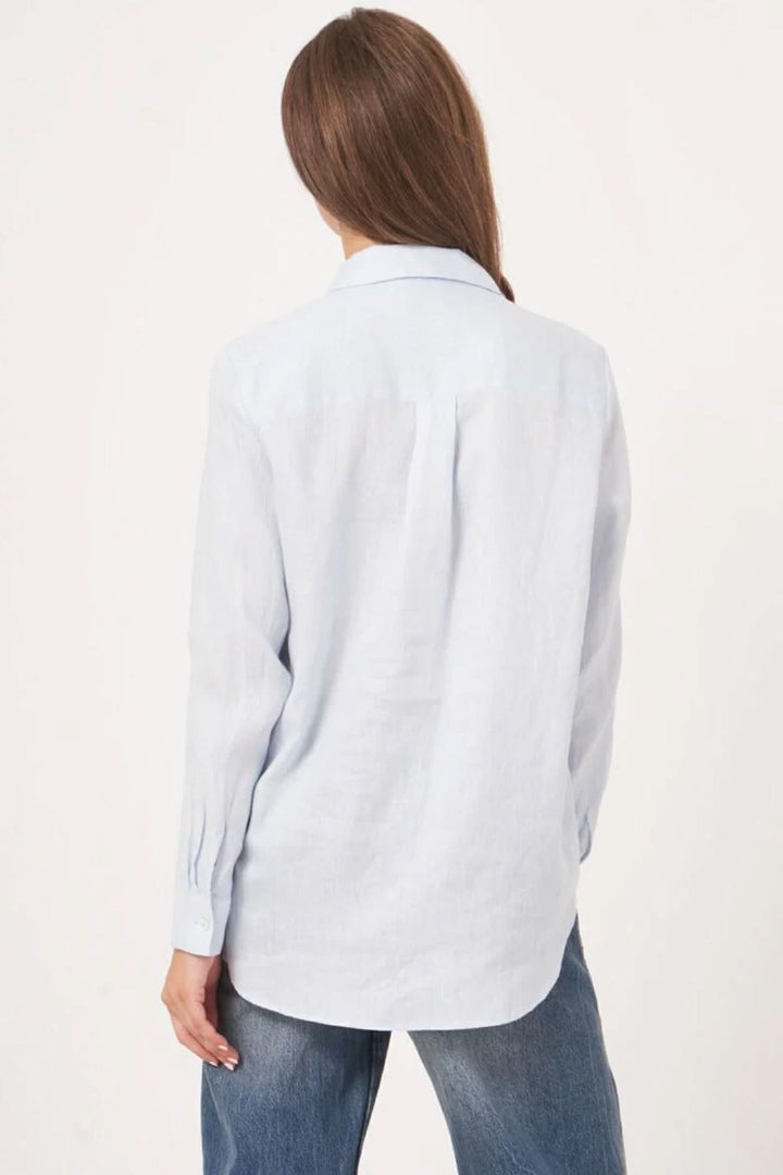 Vue arrière d'une blouse en lin à manches longues et coupe droite, portée avec un jean pour un style décontracté.