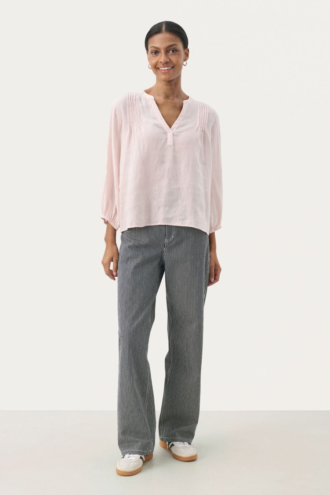 Blouse en lin Nyara, coupe droite, manches 3/4, décolleté en V, portée avec un pantalon gris.