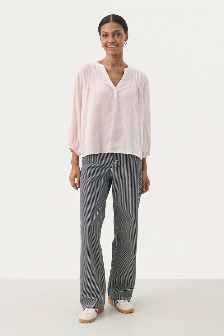 Blouse en lin Nyara, coupe droite, manches 3/4, décolleté en V, portée avec un pantalon gris.