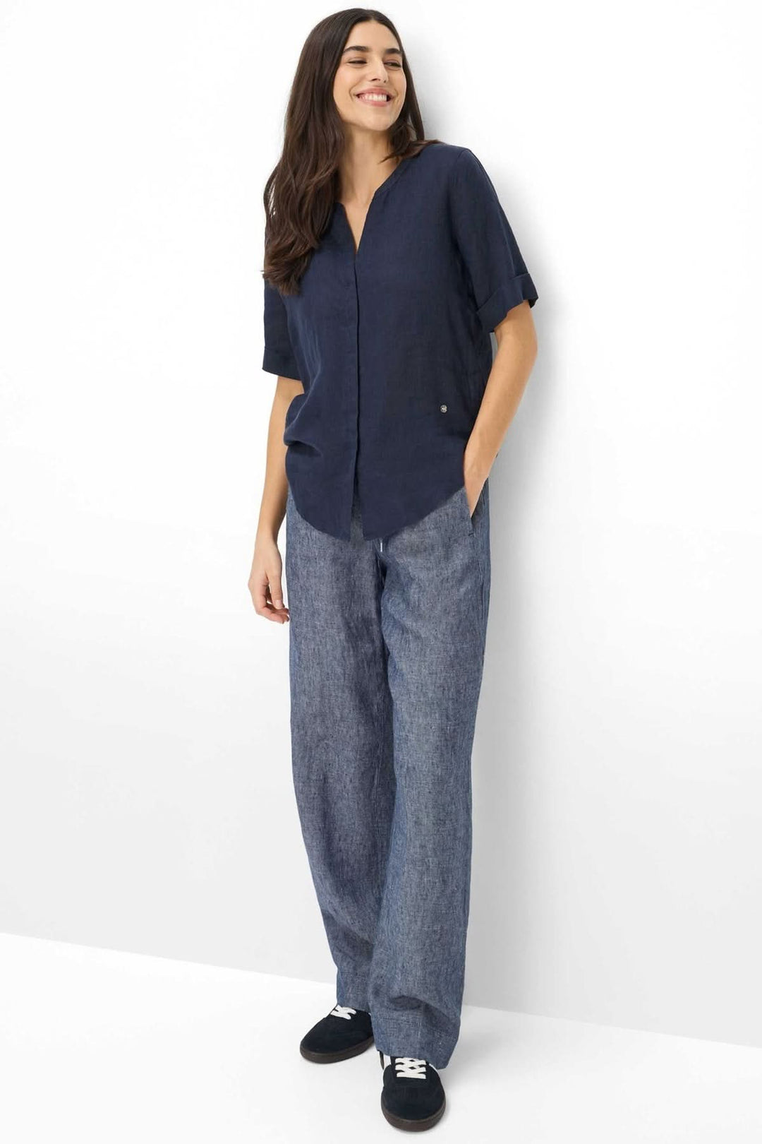 Modèle portant la Blouse en lin VERI avec manches courtes et encolure ouverte, parfaite pour un style décontracté et moderne.