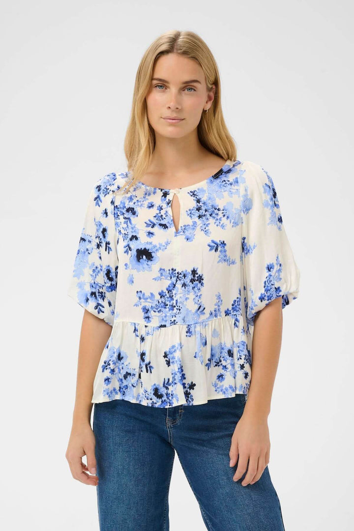 Femme portant la Blouse fleurie Azelia à imprimé floral bleu, coupe fluide et élégante, convenant à un style décontracté ou habillé.