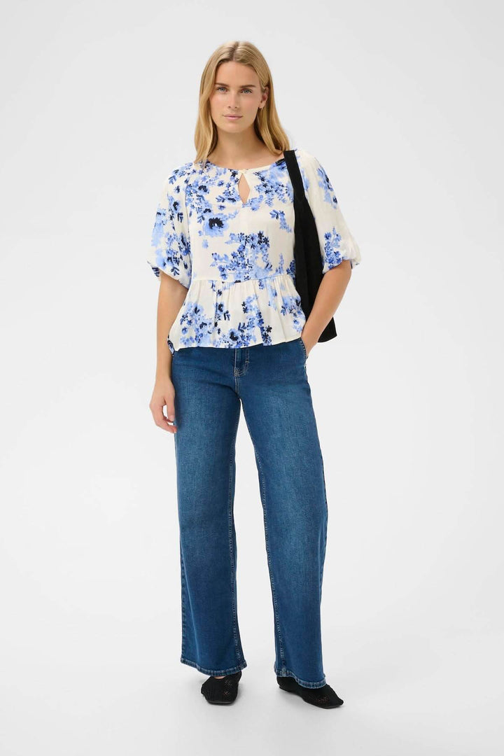 Blouse fleurie Azelia avec coupe fluide évasée, imprimé floral bleu, portée par mannequin, décontractée et élégante.