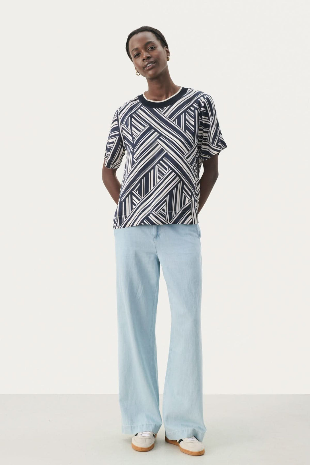 Femme portant un t-shirt à motif géométrique et un pantalon léger en denim, élégant et décontracté.
