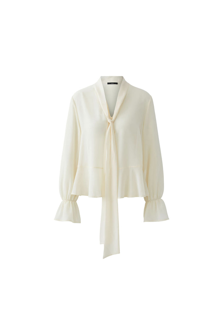 Blouse fluide à cravate col noué crème avec manches longues et volants, idéale pour une tenue élégante et raffinée.