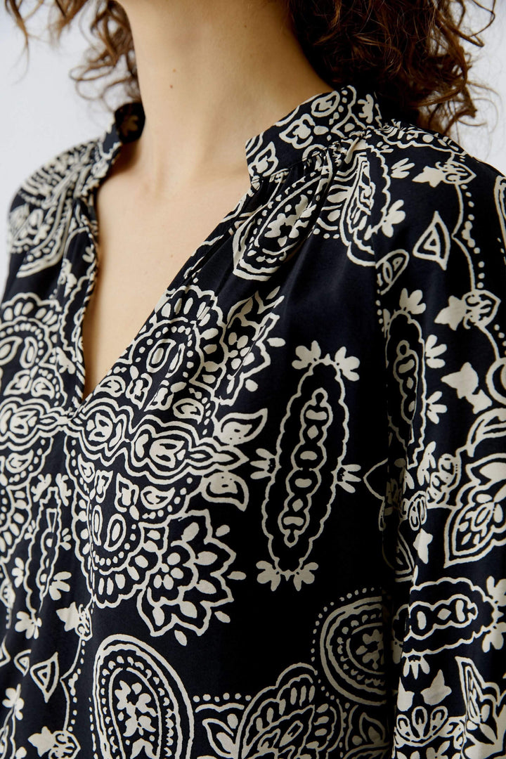 Blouse fluide imprimé graphique bohème avec encolure ouverte et coupe droite élégante.