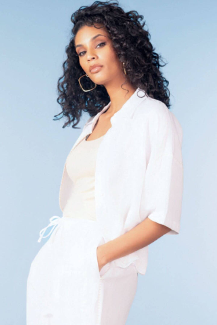 Blouse fluide manches courtes en tissu aérien portée avec allure élégante et décontractée, coupe droite et design épuré.