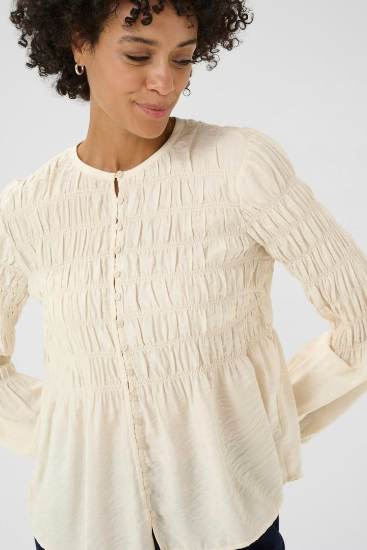 Blouse à fronces avec coupe fluide et détails texturés, encolure ronde, et patte boutonnée. Style casual chic ou raffiné.