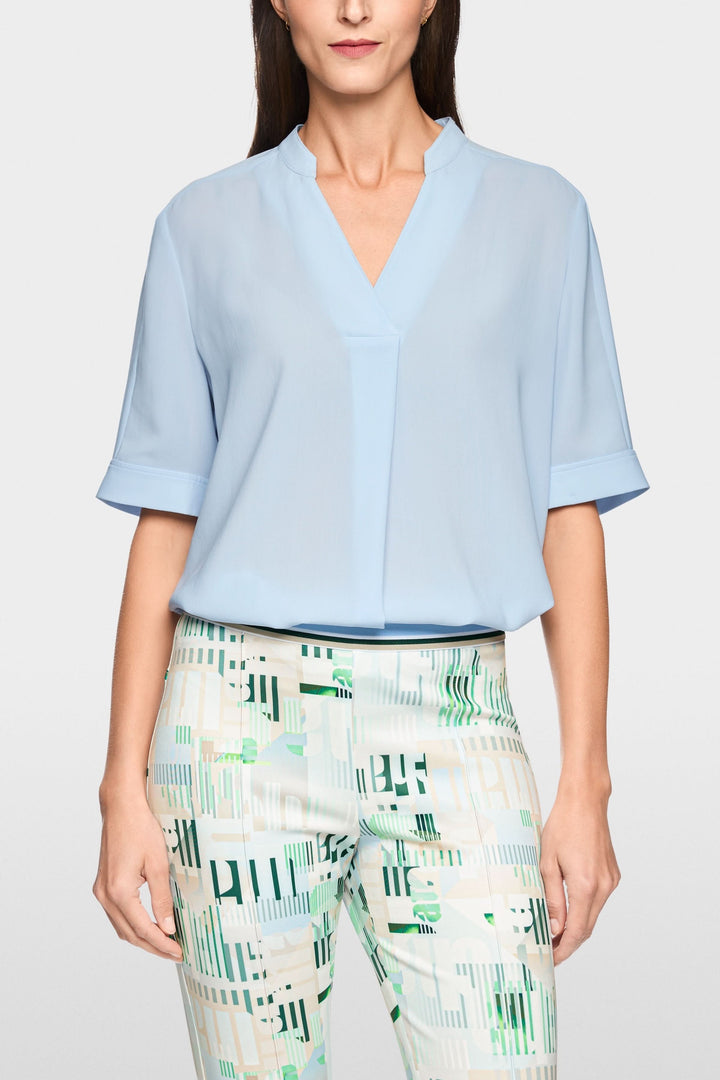 Blouse à manches courtes fluide avec encolure en V, design élégant et moderne, manches courtes à revers.