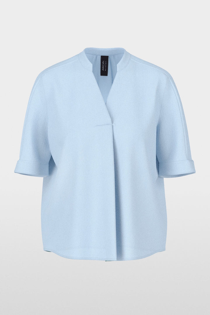 Blouse à manches courtes en tissu léger bleu clair, coupe droite fluide avec encolure en V et manches à revers.