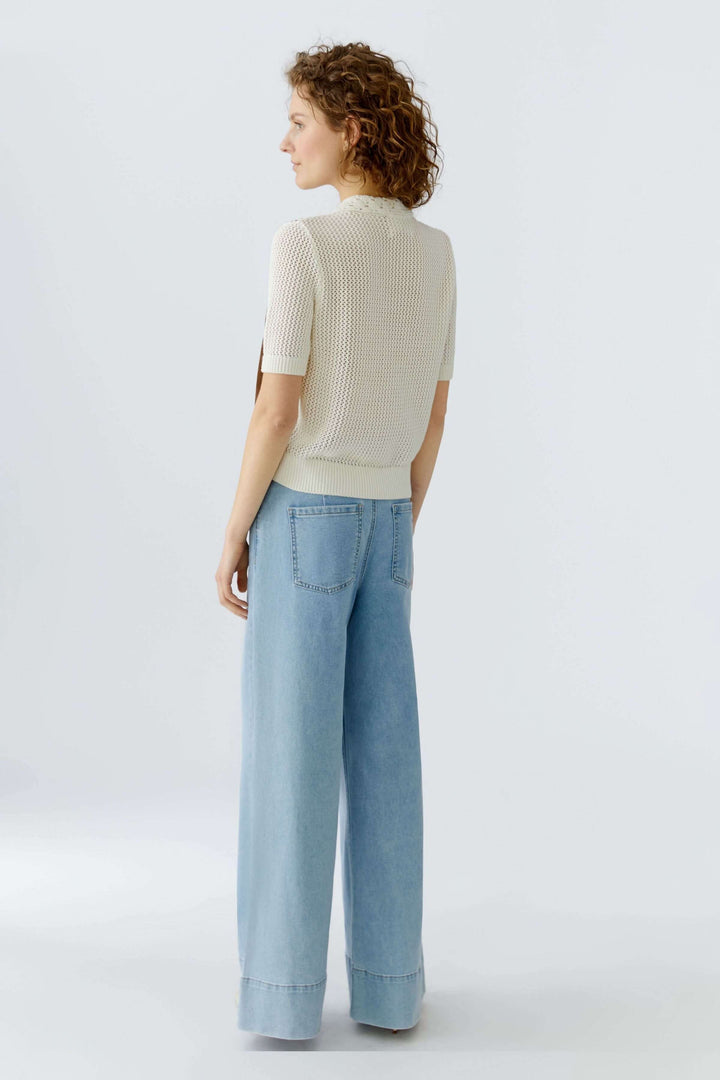 Blouse manches courtes en matières mélangées avec détails raffinés, vue de dos sur mannequin portant un jean large.
