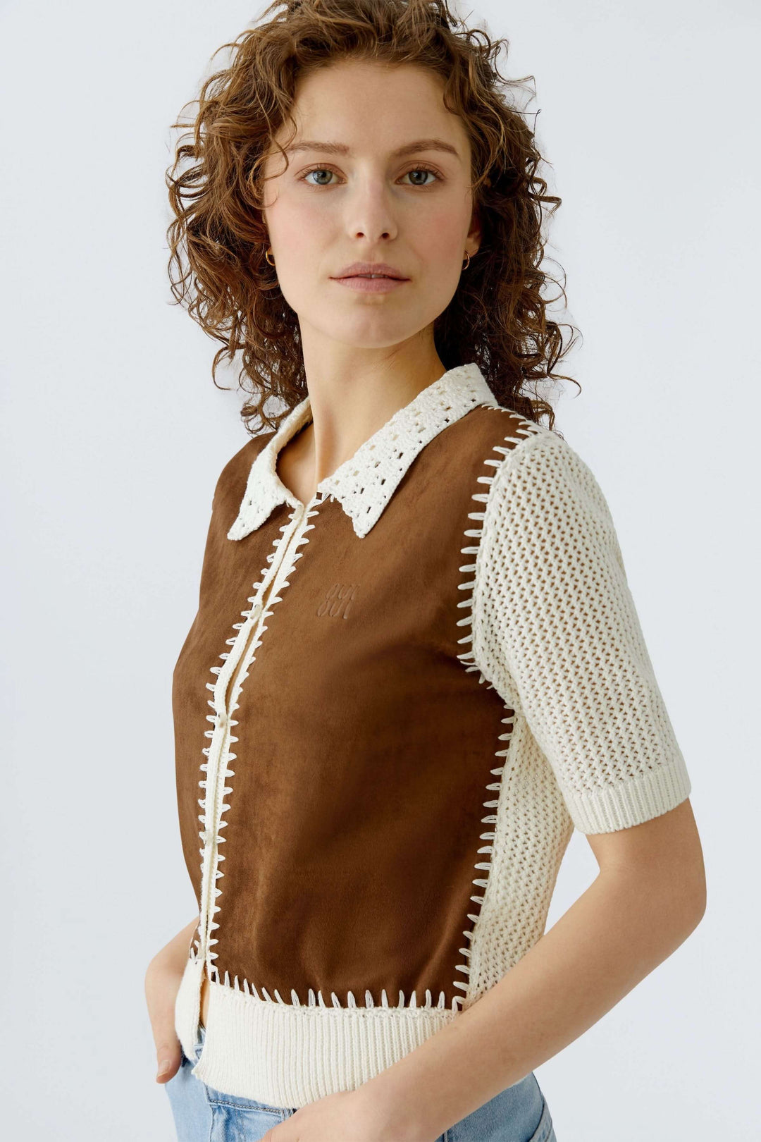 Blouse manches courtes en matières variées avec détails artisanaux et col ajouré, portée par une femme, vue trois-quarts de face.