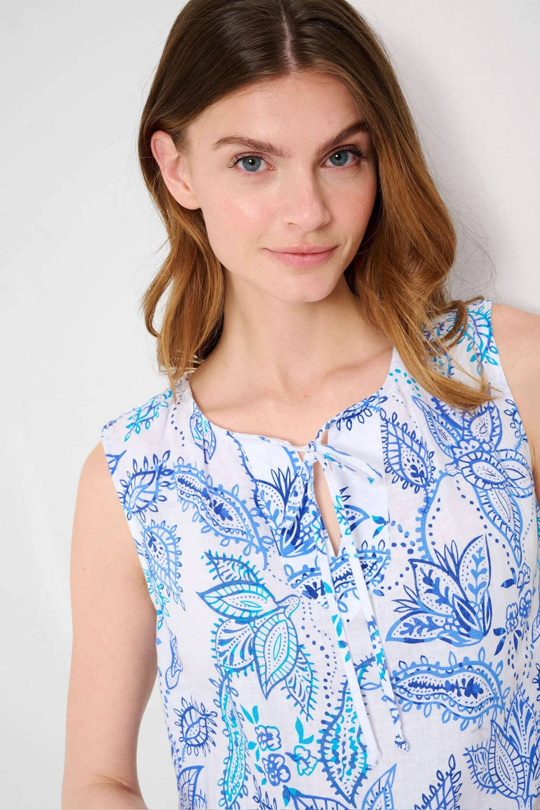 Blouse sans manches Vita avec imprimé floral en bleu et col en V, présentée par un modèle souriant.