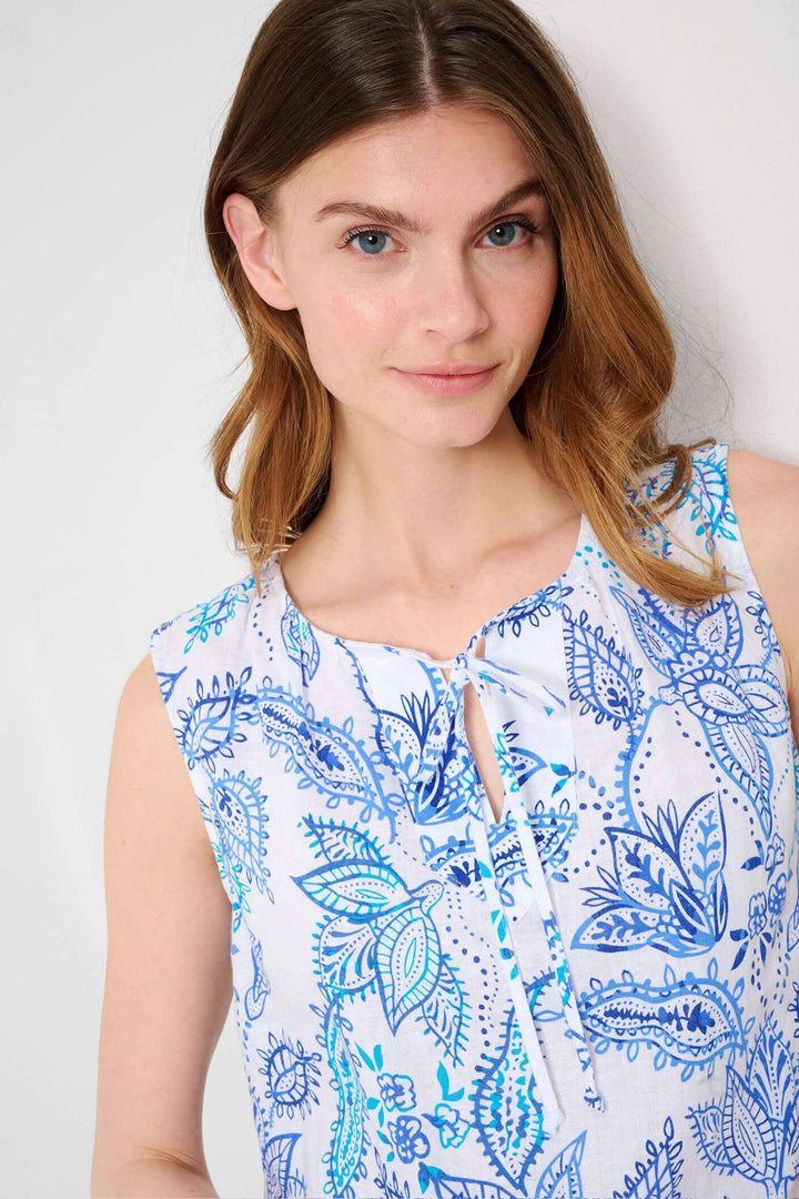 Blouse sans manches Vita avec imprimé floral en bleu et col en V, présentée par un modèle souriant.