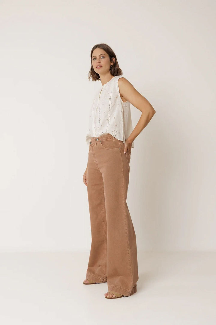 Modèle portant une blouse sans manches à détails ajourés avec un pantalon ample marron, décris moi le produit en français.