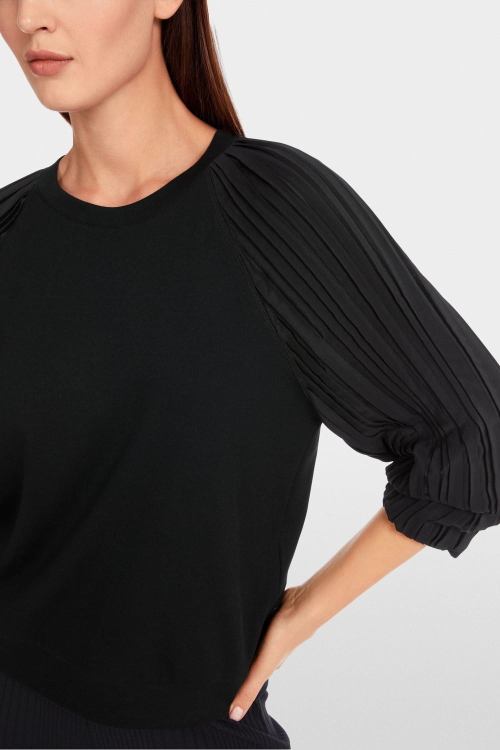 Blouse noire unie avec manches plissées en tissu doux, mélange de matières pour un style chic et confortable.
