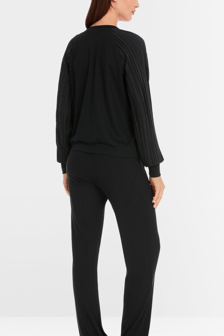 Vue arrière d'une blouse noire avec manches plissées, portée avec un pantalon assorti.