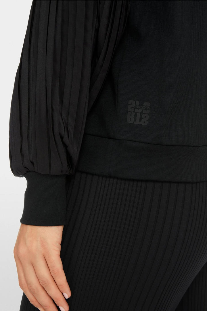 Blouse unie avec manches plissées, détail de la coupe et des textures en noir.
