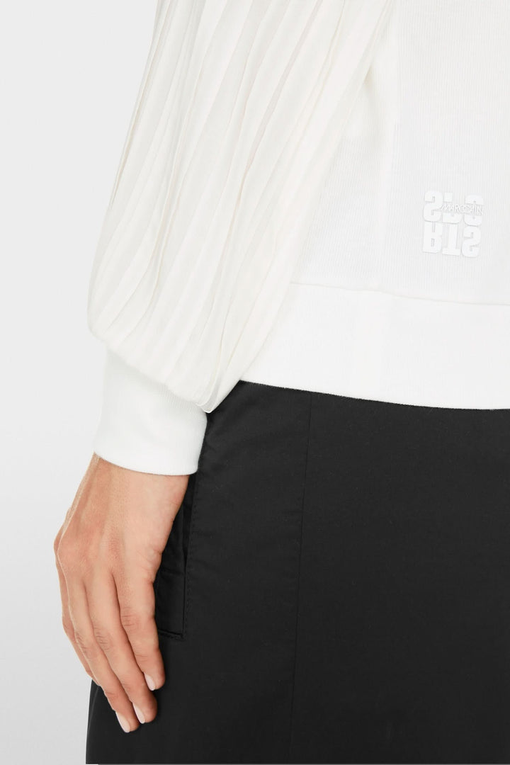 Manche plissée d'une blouse blanche, montrant la texture douce et design élégant.