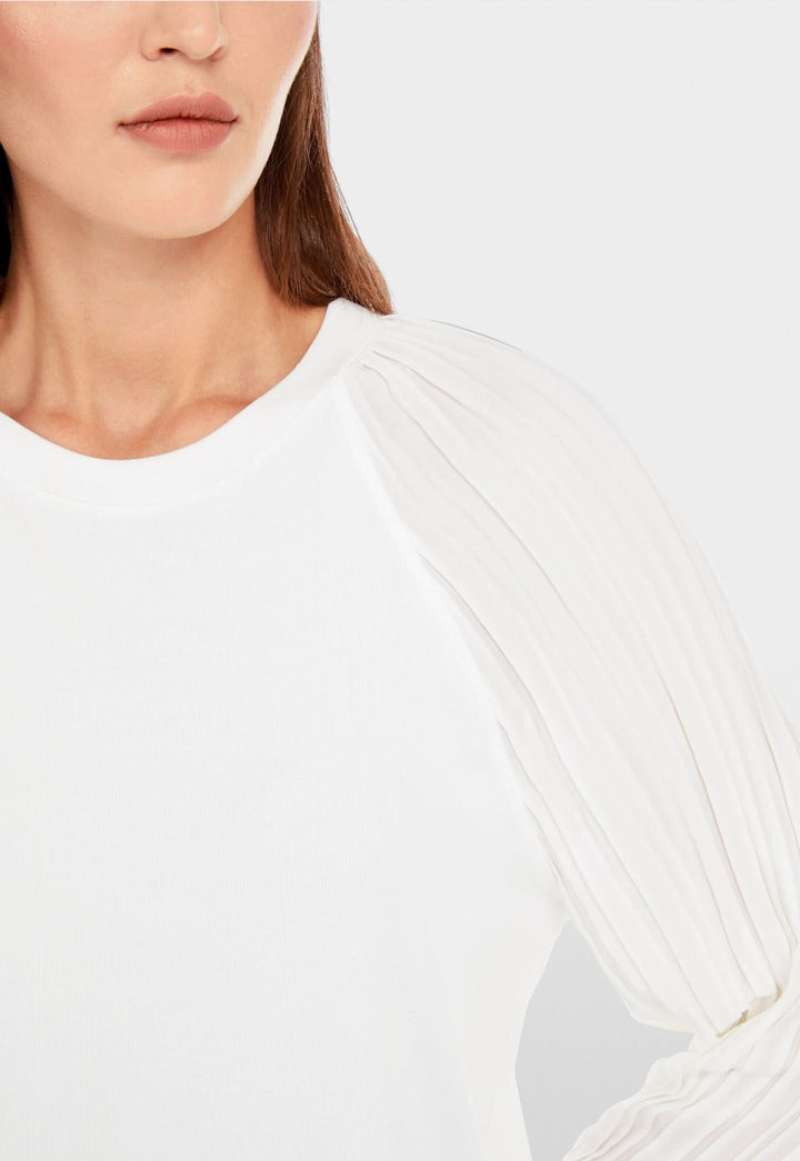 Blouse unie blanche avec manches plissées, offrant un confort élégant et un style moderne.