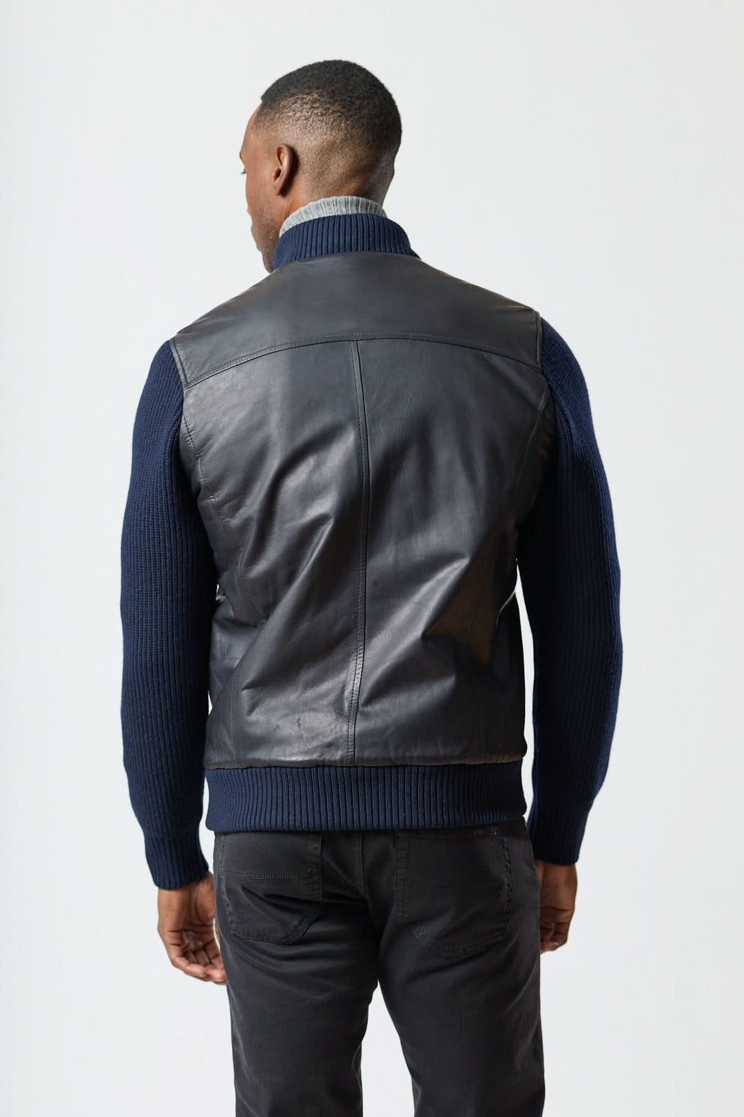 Homme portant un Blouson hybride cuir &amp; tricot zippé vu de dos, alliant élégance et confort.