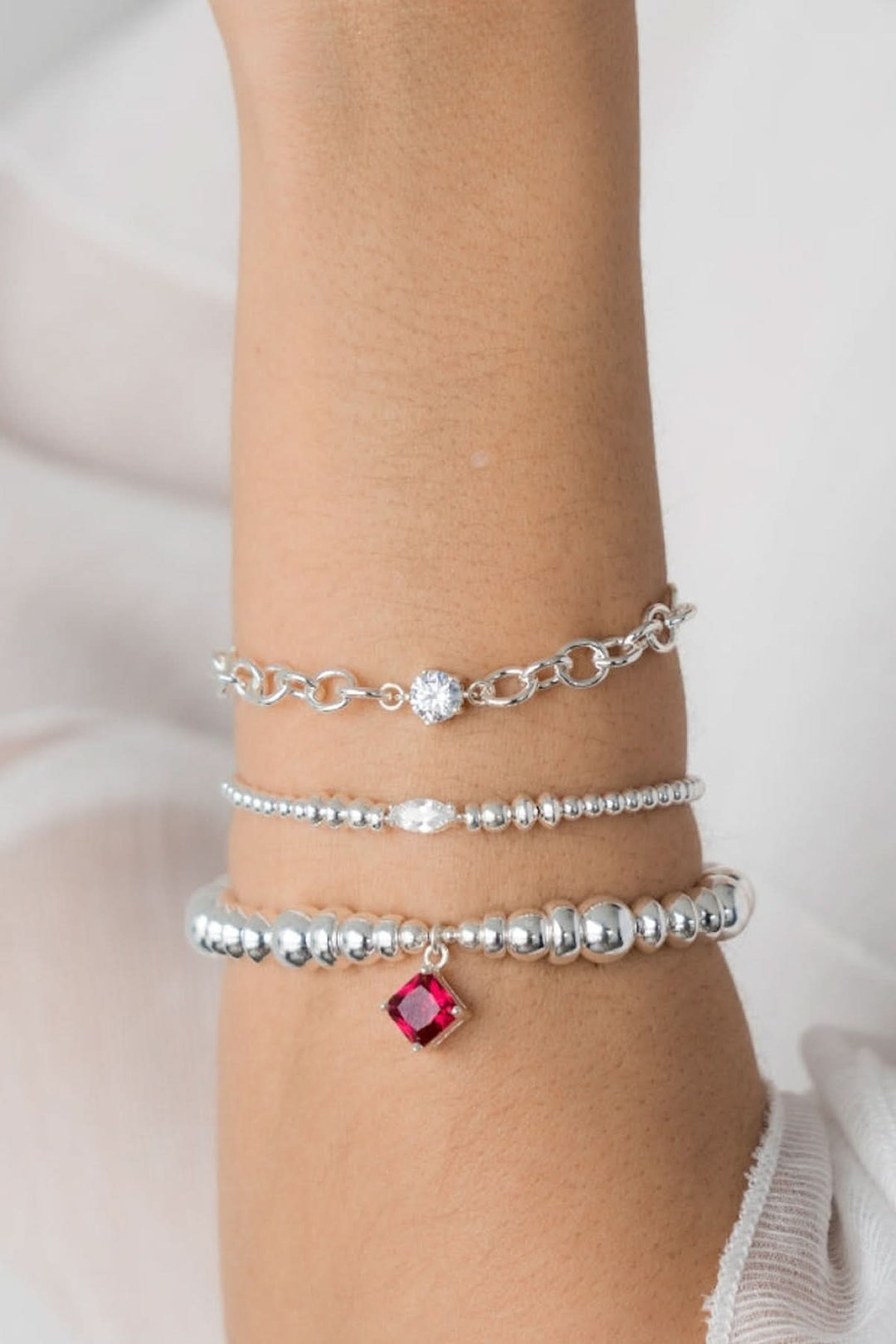 Bracelet en argent Be Sensational avec breloque en zirconium et rouge sur un poignet élégant.
