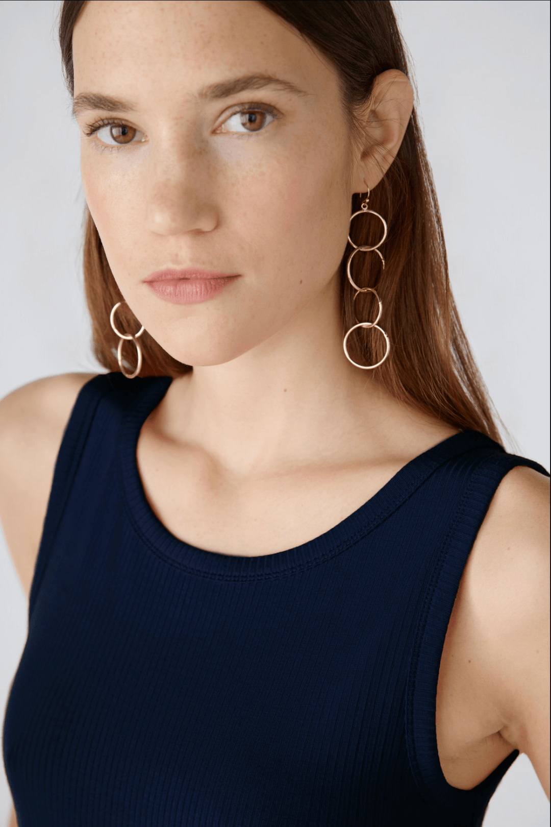Femme portant la camisole Filiz en jersey de viscose, avec des boucles d'oreilles élégantes, look moderne et féminin.