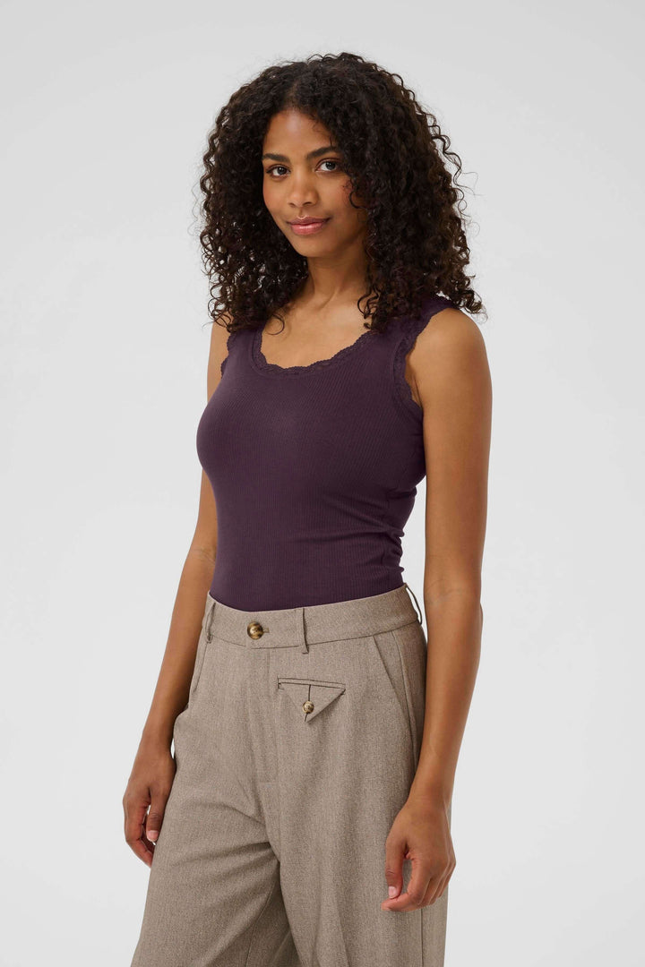 Camisole Omi en violet, coupe près du corps avec bordures en dentelle, portée avec un pantalon élégant.