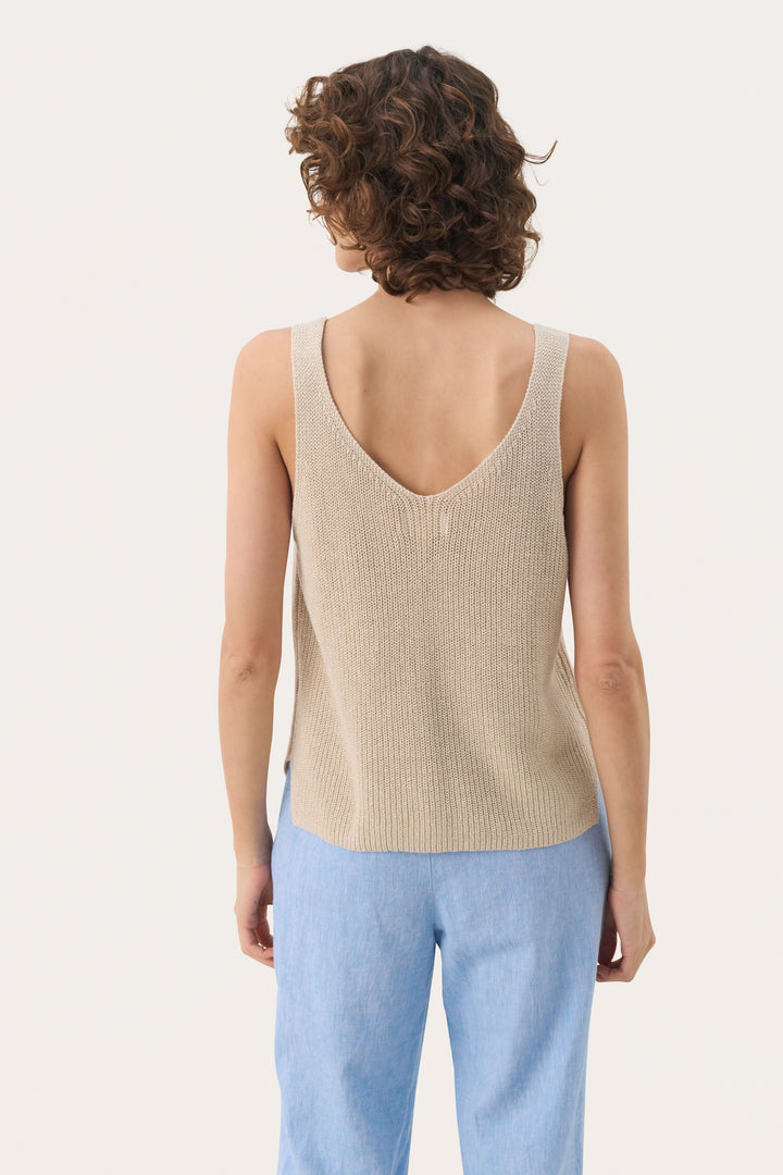 Femme portant une Camisole Rebecca tricotée col v sans manches, vue de dos, maille texturée beige et jean, look décontracté et estival.