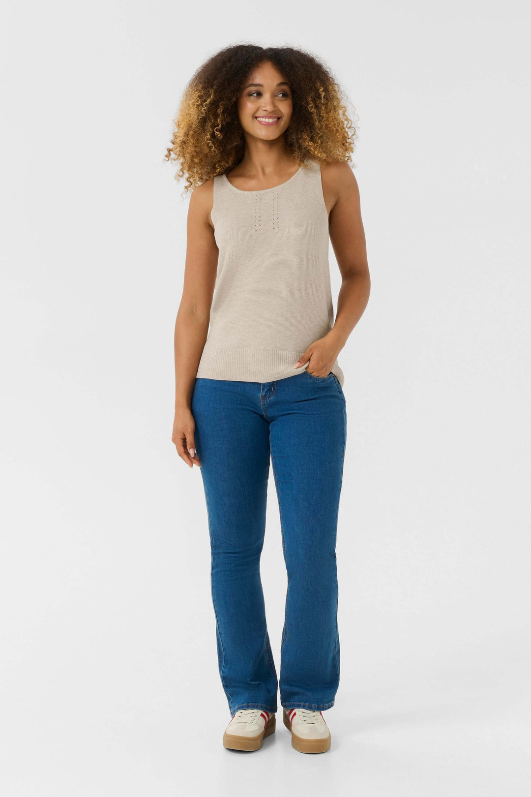 Femme portant un débardeur Sillar en maille fine, avec détail ajouré, associé à un jean bleu.