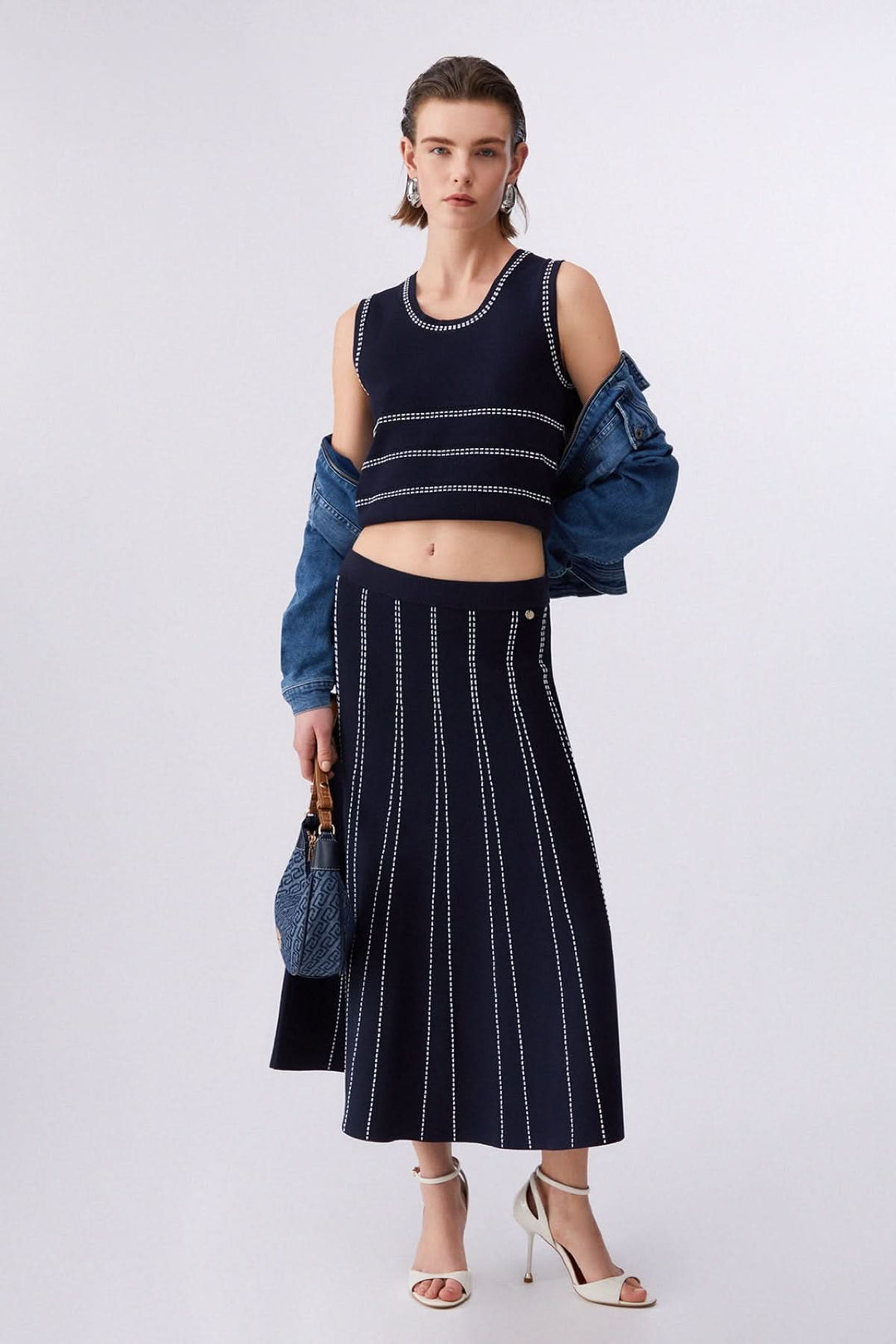 Camisole en maille sans manches à motif rayé portée avec une jupe assortie, style moderne et épuré, encolure ronde, maille structurée.