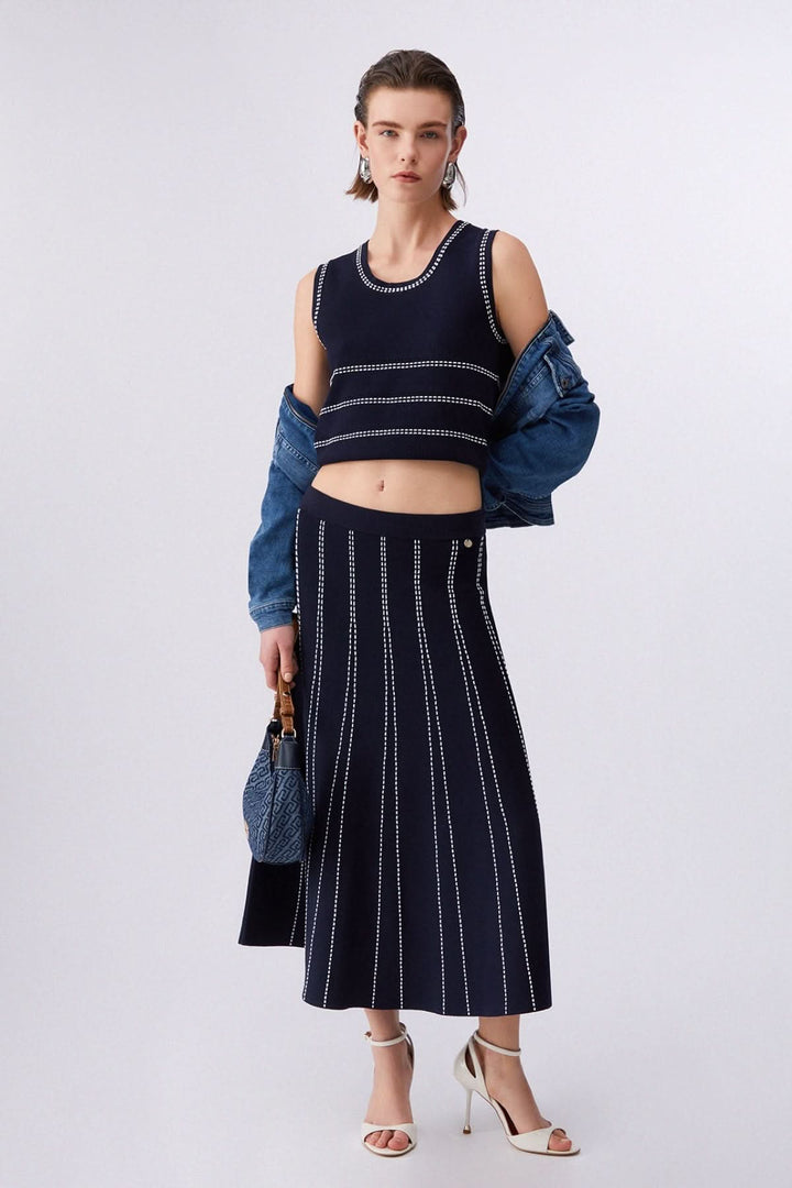 Camisole en maille sans manches à motif rayé portée avec une jupe assortie, style moderne et épuré, encolure ronde, maille structurée.